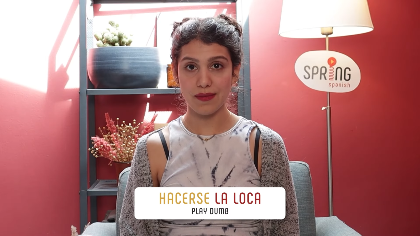 hacer conjugation hacerse la loca example with female brunette teacher in front of red wall